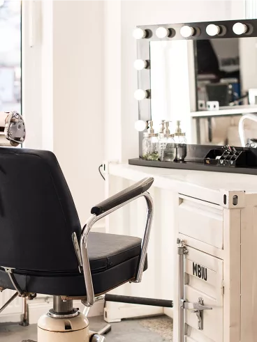 Ein Friseurstuhl mit Spiegel am Fenster