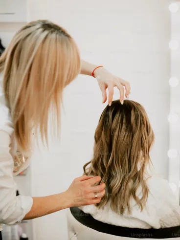 Friseurin begutachtet die langen welligen Haare einer Kundin