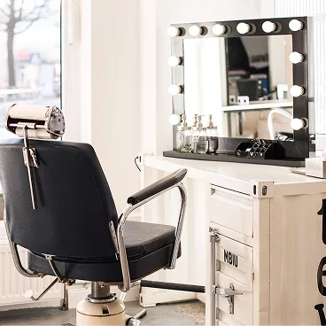 Ein Friseurstuhl mit Spiegel am Fenster